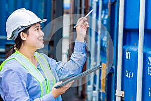 Asian young teen working in shipping logistic cargo load area use tablet wireless technology to checking customs detail of import photo