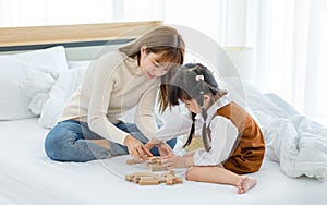 Asian young teenage female mother nanny babysitter in casual sweater and jeans sitting touching little cute preschooler daughter