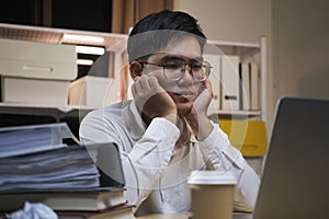 Asian young tired staff businessman using desktop computer having overwork project overnight in office.