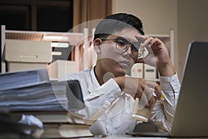 Asian young tired staff businessman using desktop computer having overwork project overnight in office.