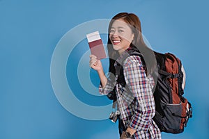 Asian young traveler in summer casual wear with passport and backpack on blue studio background