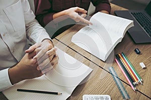 Asian young university students studying together sitting at desk in library