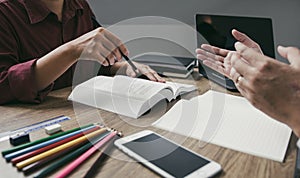 Asian young university students studying together sitting at desk in library