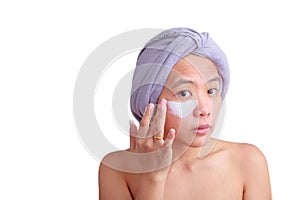 Asian young woman applying cream on her face