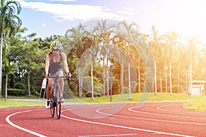 Asian young woman athletes cycling on a race track intently at outdoor sports field with sunshine