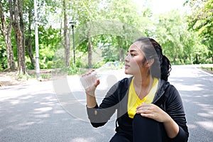 Asian young woman in black and yellow sportwear Thirsty and drinking water in bottle after exercise and running in garden