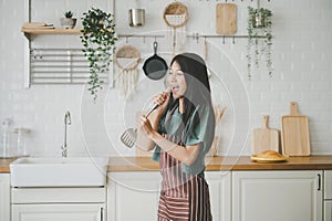 Asian young woman dancing in kitchen room