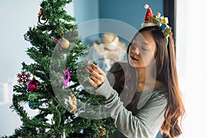 Asian young woman decorate silver pine cone to christmas tree