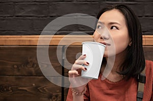 Asian young woman drinking a fresh white paper cup of water or other beverage