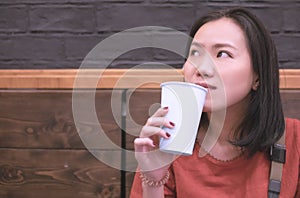 Asian young woman drinking a fresh white paper cup of water or other beverage