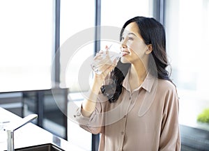 Young woman drinking water in the kitchen at home