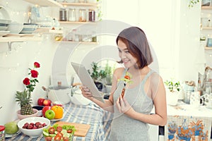 Asian young woman eating healthy food and using a tablet compute