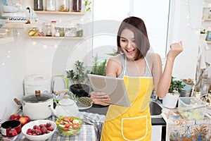 Asian young woman eating healthy food and using a tablet compute