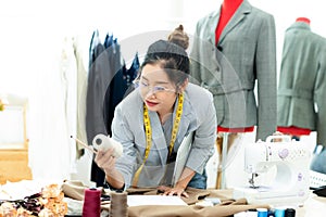 Asian young women fashion designer  working on her designer in the showroom,  Lifestyle Stylish tailor taking measurements on mann
