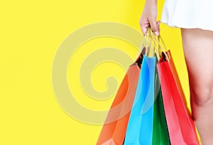 Asian young woman happy summer shopping and enjoys holiday - Pretty child girl hands holding shopping bag on yellow background