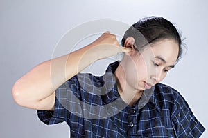Asian young woman has itchy ear and using finger to scratching ear, isolated on grey background