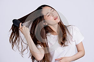 Asian young woman holding brush and show her comb, She has long hair loss after brushing her hair, hair loss in her hands. Health