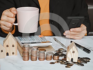 Asian young woman holding coffee cup and using smartphone shopping online-calculate home salary and expenses. concept saving money