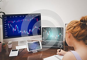 Asian young woman interacting with laptops, phones, and tablets with featuring stock tickers or graphs, cryptocurrency and new tra