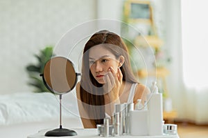 Asian young woman looking in mirror worry about pores facial skin problem with acne and dry skin,Skin care concept
