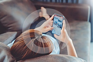 Asian young woman lying down on sofa resting browsing internet with Smart Phone holding credit card online shopping concept