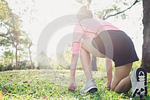 Asian young woman on mark to set ready for jogging exercise to buld up her body on glass in warm light morning.