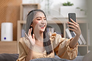 Asian young woman meeting with business team via video conference call at Home.Hand up Greetings with family group in online video