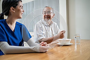 Asian young woman nurse taking care of disabled handicapped senior elderly man at nursing home. Caregiver Therapist doctor serving