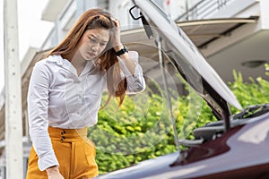 Asian young woman open car hood looking car engine after found car problem