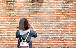 Asian young woman is photographing a brick wall. Before she crossed it. Positive concept.