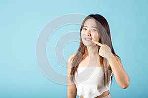 Asian young woman pointing to her strong white teeth