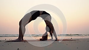 Asian young woman practice Yoga bridge Pose on the sand and beach with sunset