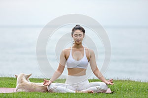 Asian young woman practice yoga lotus pose to meditation with dog on the beach feeling so happiness and cheerful