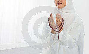 Asian young woman praying with Al-Qur`an and prayer beads