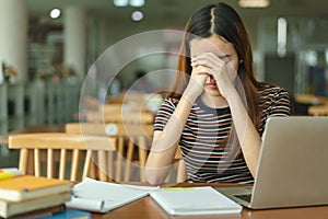 Asian young woman reading the book in library and closed her eyes to rest