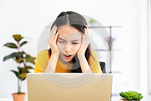 Asian young woman seriously working on computer laptop in house