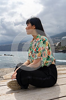 Asian young woman sitting cross-legged.