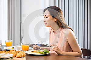 Asian young woman sitting kitchen table food having eating healthy breakfast at home