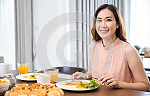Asian young woman sitting kitchen table food having eating healthy breakfast at home