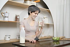 Asian young woman in sportswear drinking milk in kitchen at home , healthy lifestyle concept