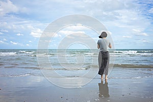 Asian young woman standing facing the sea. Feeling really lonely, heartbroken sea like a nursery of clearing the mind. The concept