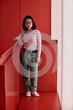 Asian Young Woman Standing in Red Space and Looking at Camera