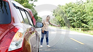 Asian young woman stopping a car and needs a help with her broken car on road.