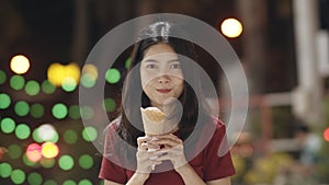 Asian young woman travel in Bangkok, Thailand, beautiful female feeling happy walking and eating ice cream at The Khao San Road.