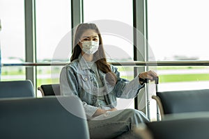 Asian young woman traveller wearing face maks at airport Due Covid-19 flu virus pandemic