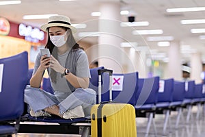 Asian young woman traveller wearing face maks using mobile phone at airport photo