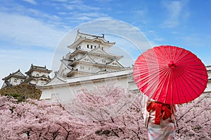 Asian young woman traveller wearing japanese traditional kimono with red umbrella sightseeing at famous destination cherry blossom