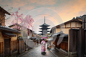 Asian young woman traveller wearing japanese traditional kimono with red umbrella sightseeing at famous destination Sannen Zaka