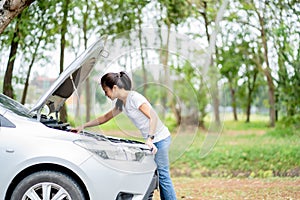 Asian young woman trying to fix this broken car on the street