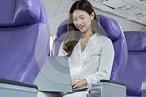 Asian young woman using laptop sitting near windows at first class